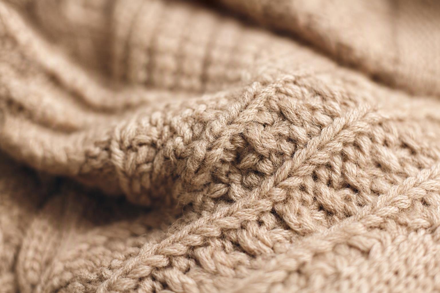 a macro view of a knitted sweater surface showing stitch definition, yarn twist and loft
