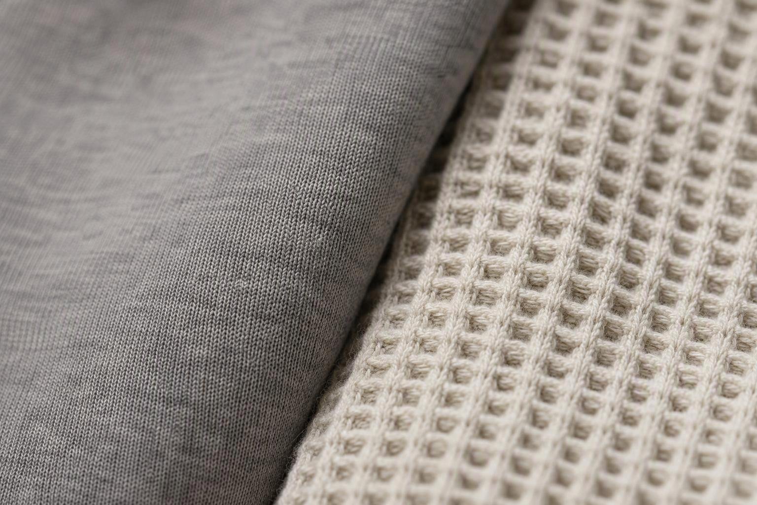 a side-by-side macro of pima jersey and pima piqué surfaces showing the flat face of jersey against the raised waffle of